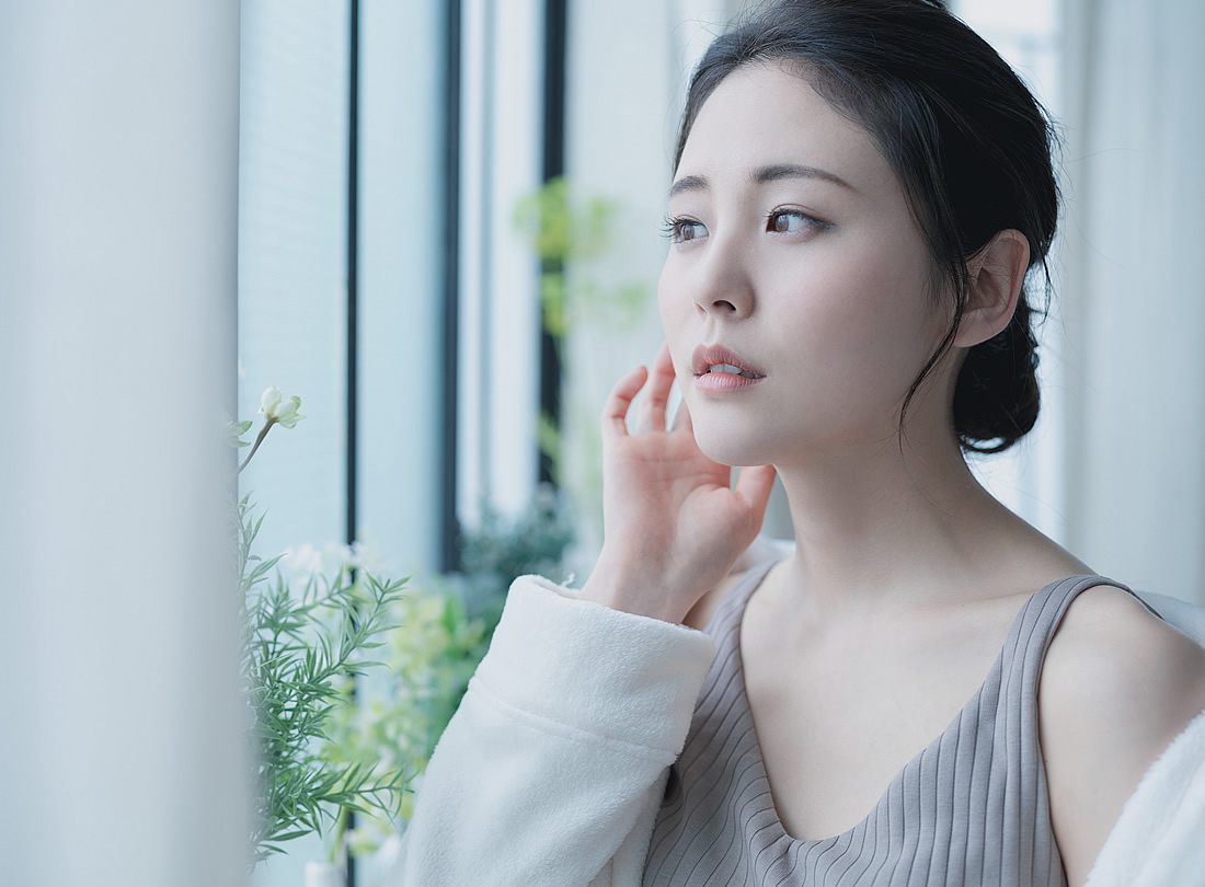 自然光の中で肌に手を添える女性